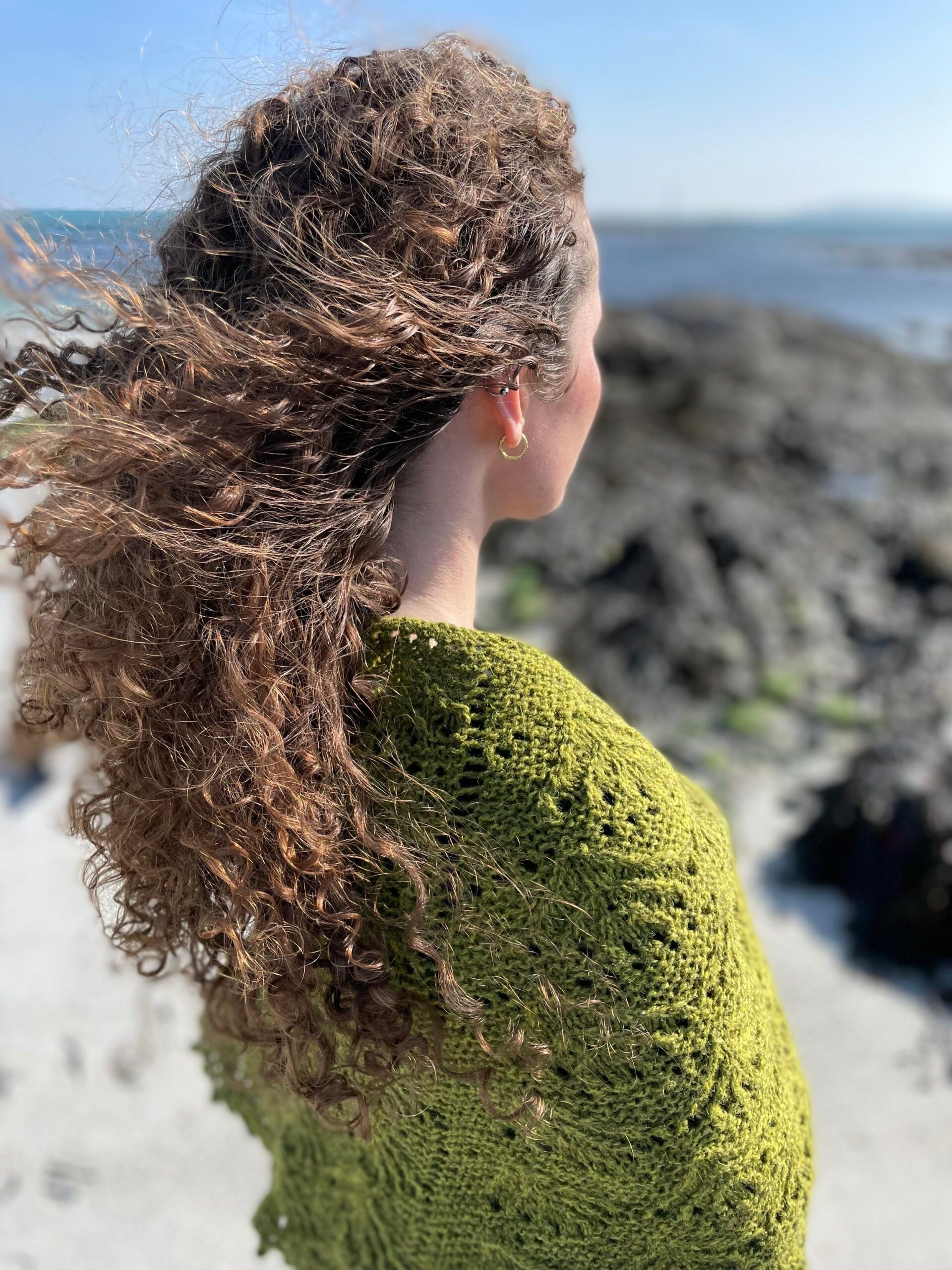 Beachcomber Shawl by Emma Vining. A green shawl, worn outside on the coast